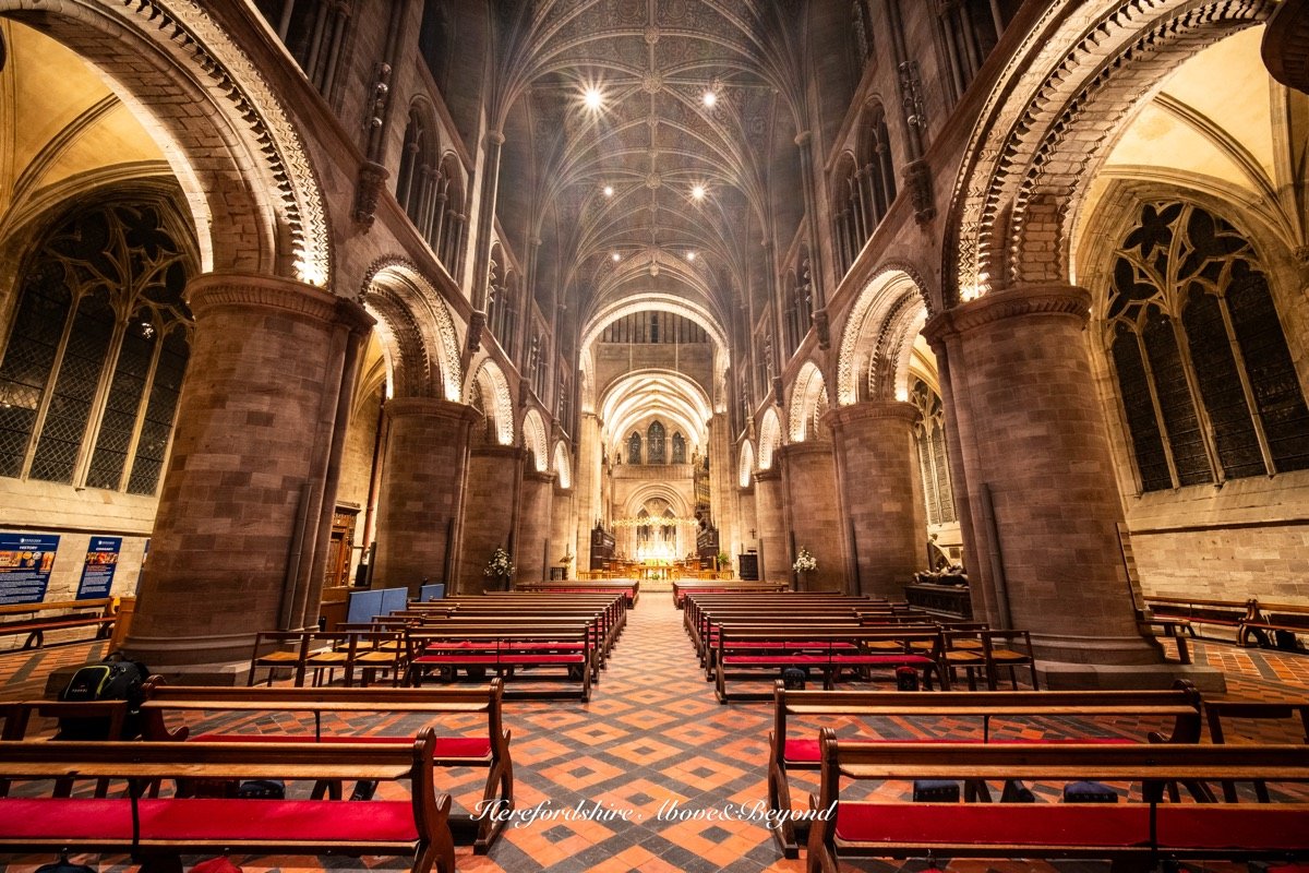 Interior of Hereford Cathedral looking along the nave, with its patterned tiled floor and vaulted ceiling