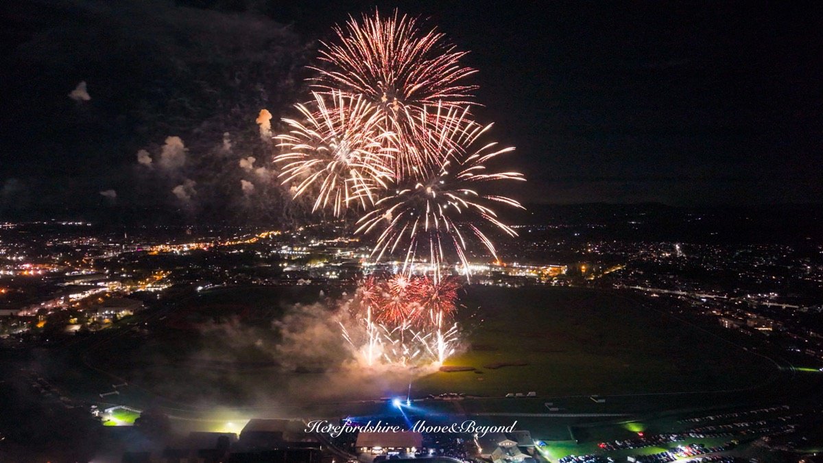 Aerial view of a fireworks display over a racecourse at night