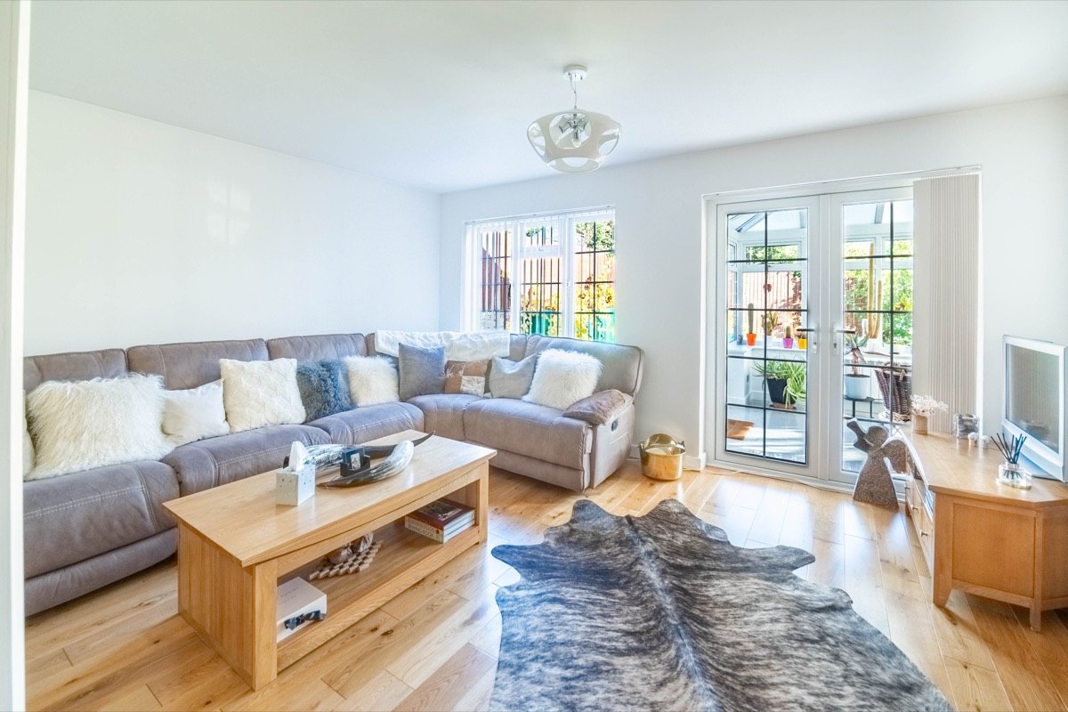 Living room with a grey corner sofa, oak coffee table, wooden flooring and French doors to the conservatory
